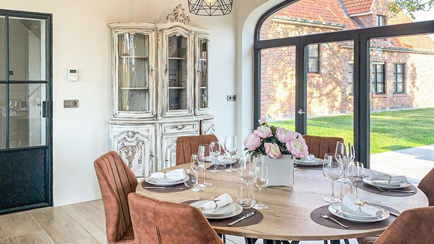 A dining area with a round table set for six, surrounded by brown upholstered chairs. A white cabinet with glass doors is to the left. - Amazing home in Diksmuide with WiFi (Diksmuide)