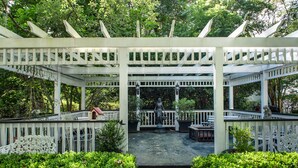 A white gazebo with a statue in the center, surrounded by lush greenery and a small garden area. - Winter Discounts/ We love pets and they love our amenities (Summerville)