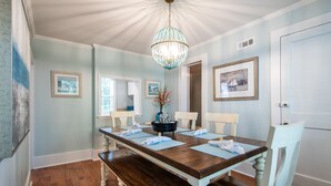 A dining room with a wooden table, white chairs, a chandelier, and framed pictures on the walls. - Winter Discounts/ We love pets and they love our amenities (Summerville)