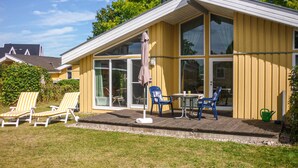 Un edificio giallo con ampie finestre, un patio con poltrone relax e un tavolino.