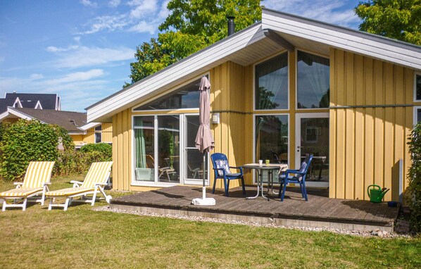 A yellow building with large windows, a patio with lounge chairs, and a small table. - Beautiful home in Rechlin with sauna (Rechlin)