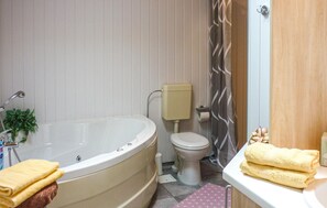A bathroom with a bathtub, toilet, and a shower curtain. - Beautiful home in Rechlin with sauna (Rechlin)