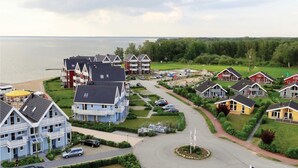 Una zona residenziale costiera con diverse case, una strada principale e uno specchio d'acqua sullo sfondo.