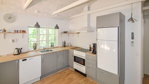 Une cuisine moderne dotée d’un plan de travail en bois, d’appareils électroménagers en acier inoxydable et d’une grande fenêtre qui laisse entrer la lumière naturelle.