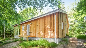 Une cabane en bois avec une seule porte et un petit porche.