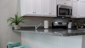 A kitchen with white cabinets, a microwave, a sink, and three turquoise bar stools. - New Construction, Warm Coastal Feel, Home Away From Home
Covered Parking (Myrtle Beach)