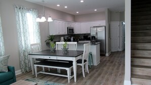 A modern kitchen with white cabinets, a stainless steel refrigerator, and a dining area with a table and chairs. - New Construction, Warm Coastal Feel, Home Away From Home
Covered Parking (Myrtle Beach)
