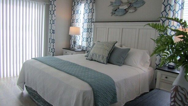 A neatly arranged bedroom with a large bed, a bedside table with a lamp, and a wall-mounted fish decoration. - New Construction, Warm Coastal Feel, Home Away From Home
Covered Parking (Myrtle Beach)