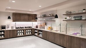 A modern kitchen with wooden cabinets, white countertops, and various kitchen appliances.