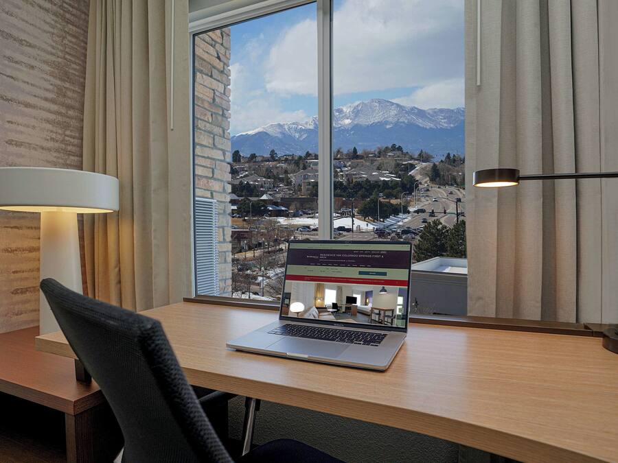 Una computadora portátil sobre un escritorio con vista a las montañas a través de una ventana.