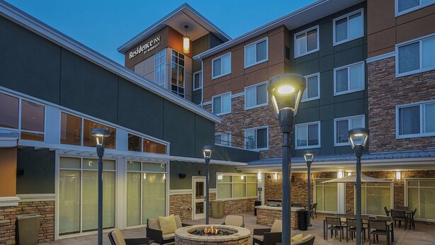 A hotel with outdoor seating, a fire pit, and a stone facade.