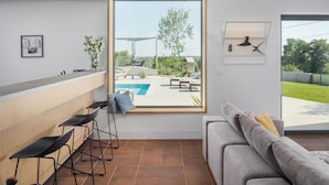 A modern living room with a large window, a pool, and a view of the outdoors. - Beautiful home in Barban (Barban)