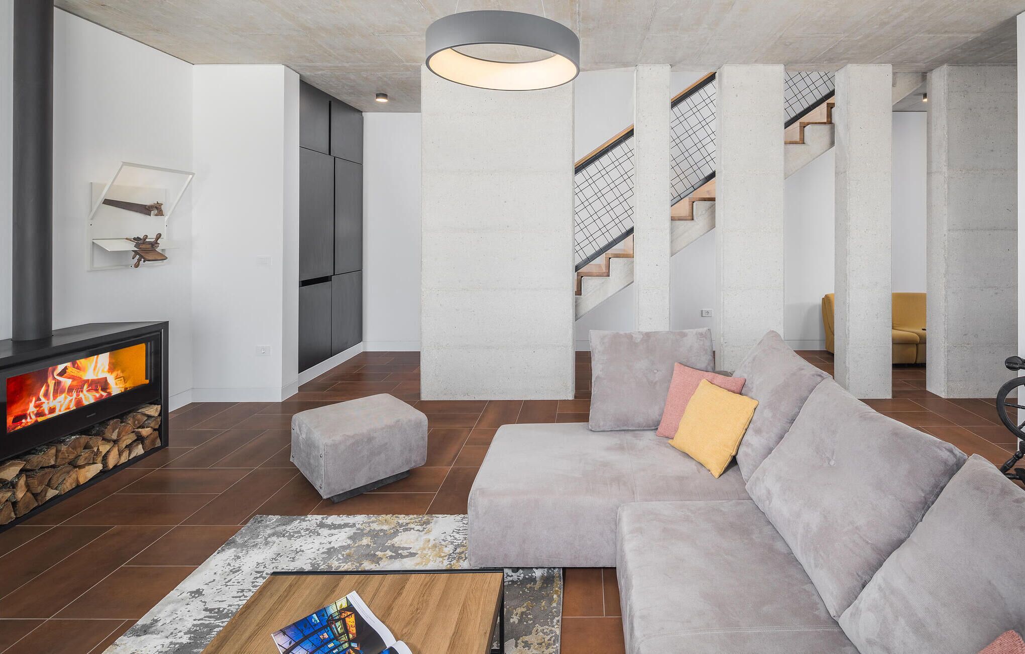 Un salon moderne avec un canapé d’angle, une cheminée et un escalier.