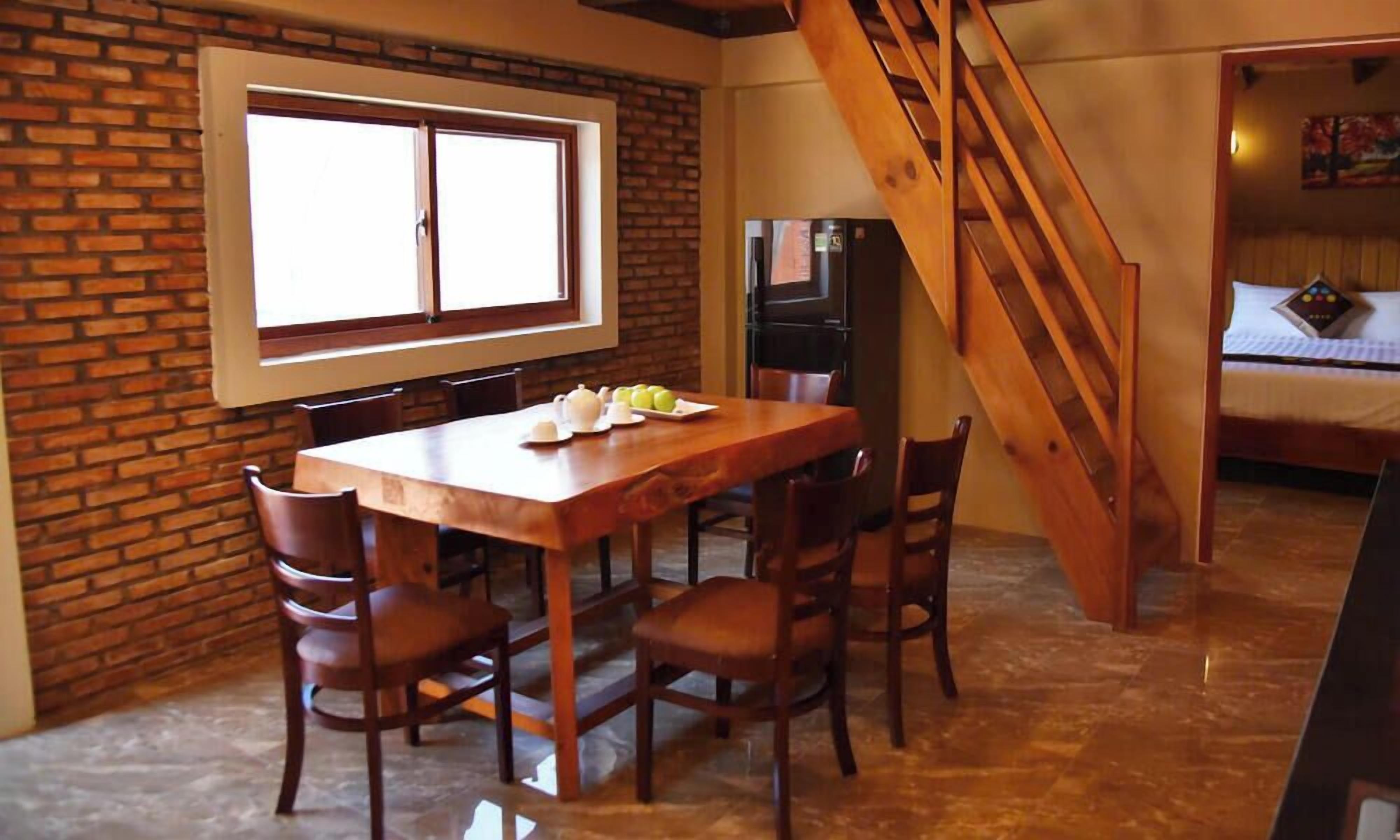 A dining area with a brick wall, a wooden table, and chairs.