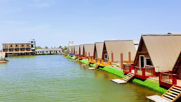 Une rangée de cabines colorées, en forme de bateau, avec un pont en arrière-plan.