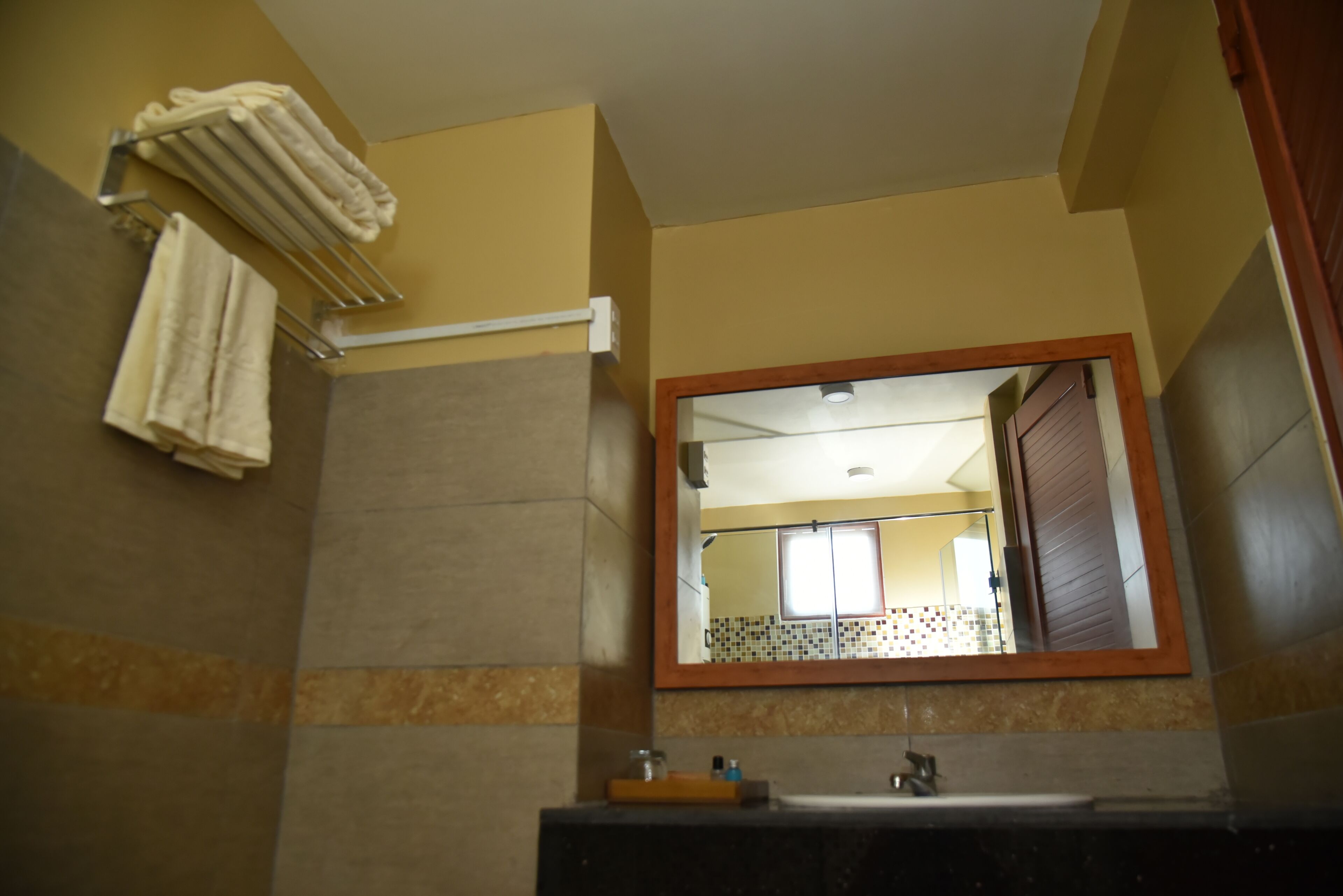 A bathroom with a mirror, towel rack, and sink.