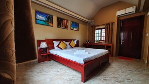 Une chambre à coucher avec un grand lit, une table de chevet, un bureau et une fenêtre avec des rideaux.