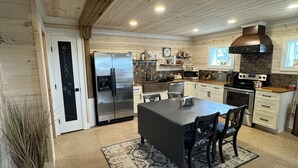 A modern kitchen with wooden ceiling beams, a central island, stainless steel appliances, and a welcoming sign. - 2A2J Barn pool Getaway 9 miles to WEC (Wilmington)