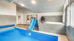 Ein Swimmingpool mit blauer Rutsche, einem Whirlpool und Blick auf einen Küchenbereich.