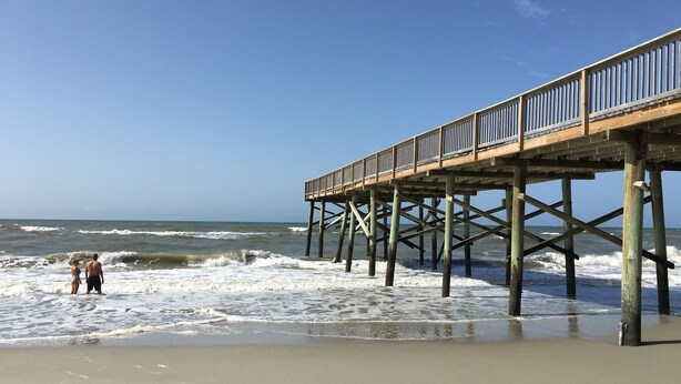 A wooden pier extending into the ocean with a clear sky above. - 2nd Floor Beachside Condo•Private Beach Access•Pool•Kitchen•Pet-Friendly (Atlantic Beach)