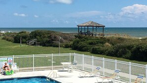 A pool area with a gazebo overlooking the ocean, surrounded by a white fence and equipped with lounge chairs. - 2nd Floor Beachside Condo•Private Beach Access•Pool•Kitchen•Pet-Friendly (Atlantic Beach)