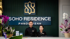 Un mostrador de recepción en Soho Residence, con un logotipo, el nombre del lugar y empleados detrás.