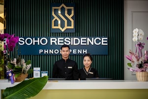 Un mostrador de recepción en Soho Residence, con un logotipo, el nombre del lugar y empleados detrás.