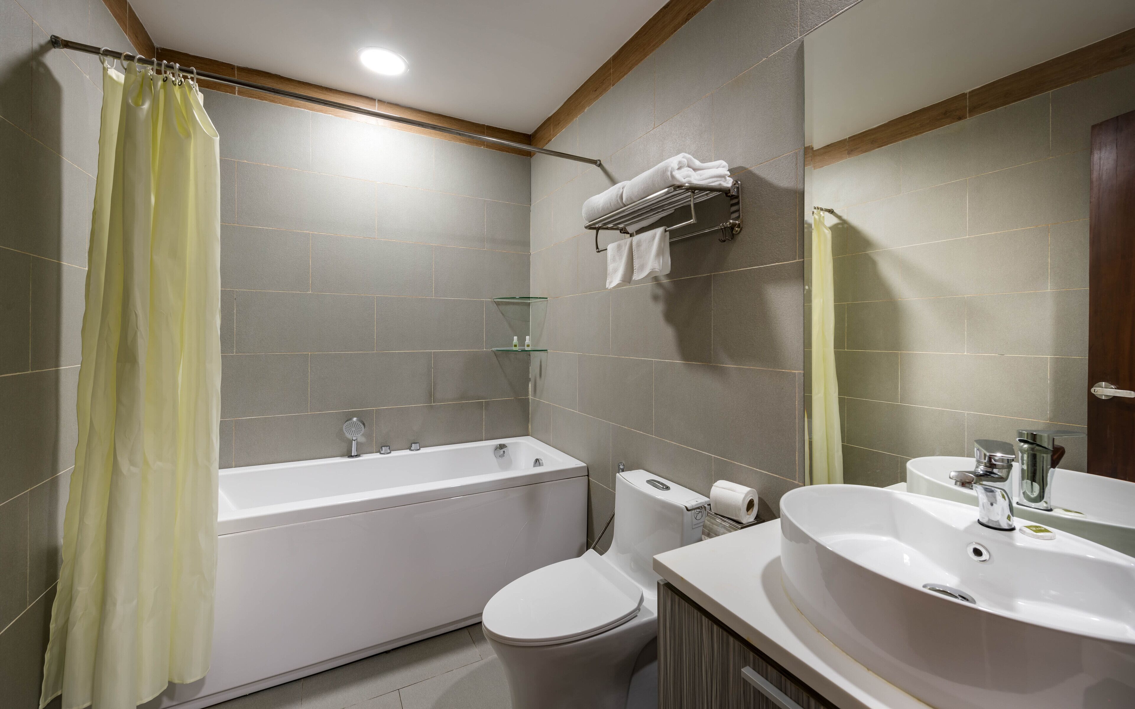Een badkamer met een badkuip, toilet, wastafel en een douchecabine van glas.