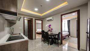 Una habitación de hotel moderna con cocina, una mesa de comedor con sillas, una cama y un equipo de aire acondicionado.