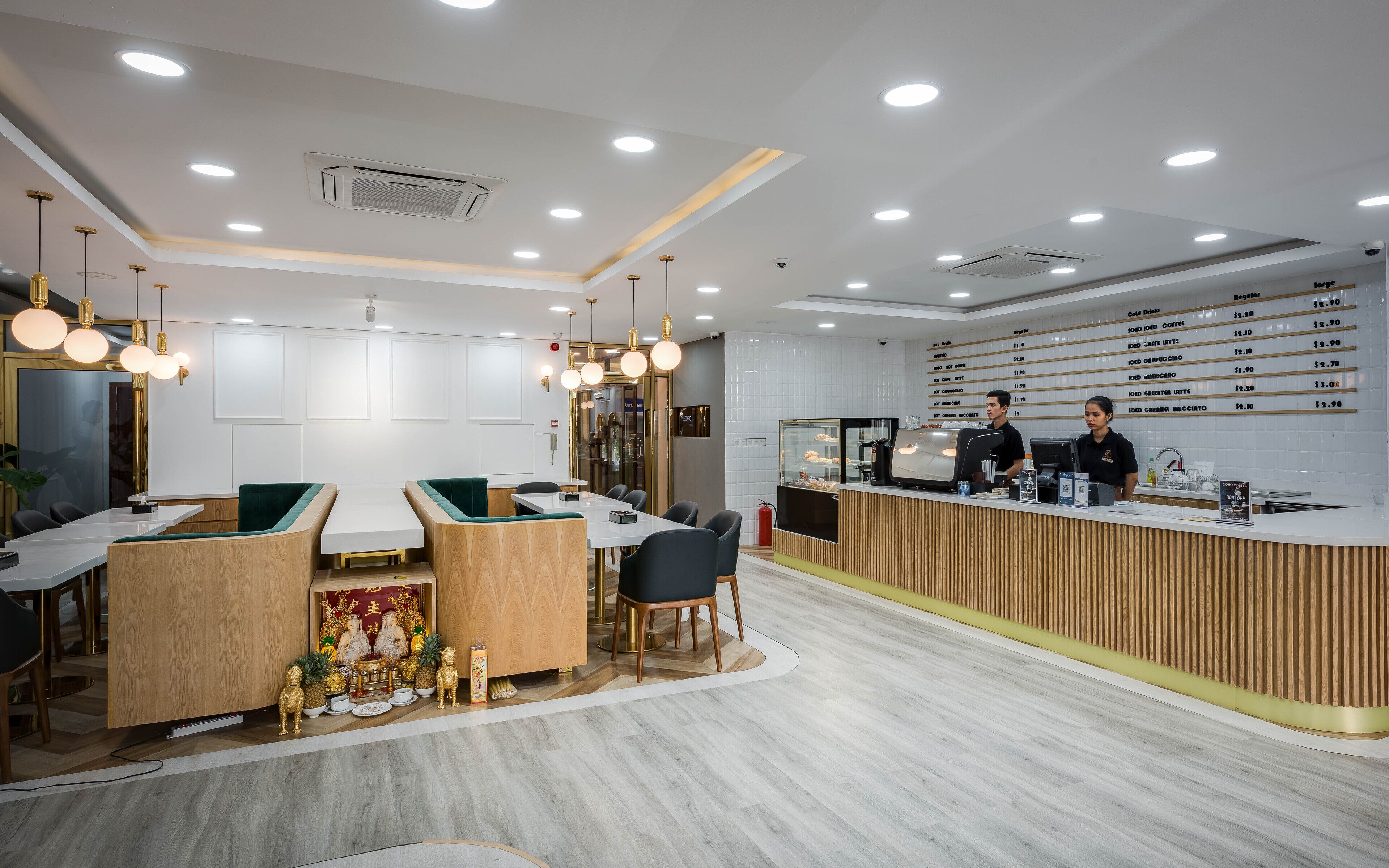 A modern cafe interior with wooden furniture, a counter with staff, and a menu board.