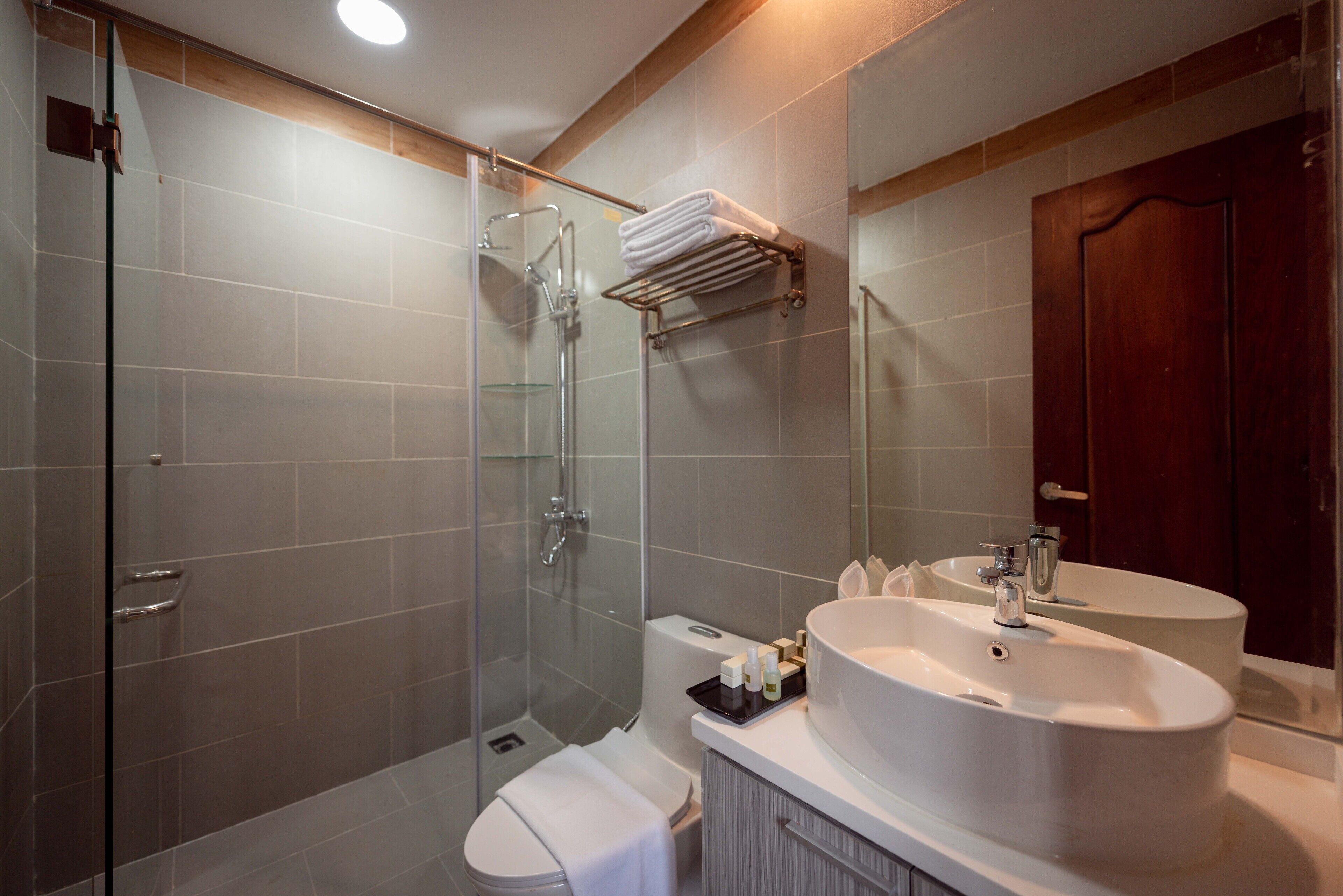 Une salle de bain moderne avec une douche à parois de verre, des toilettes blanches et un grand lavabo blanc avec un miroir au-dessus.