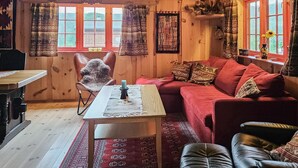 A cozy cabin interior with a wooden dining table, a red sofa, and a leather armchair. - 2 bedroom awesome home in Nordberg (Nordberg)