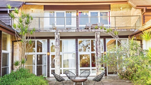 A two-story building with a balcony, large windows, and outdoor seating. - Razorback Dream Farmhouse: 10BR, Space & Serenity (Razorback)