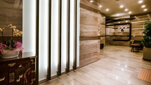 Un área de recepción de hotel moderna con suelo de mármol, mostrador de recepción y zona de estar.