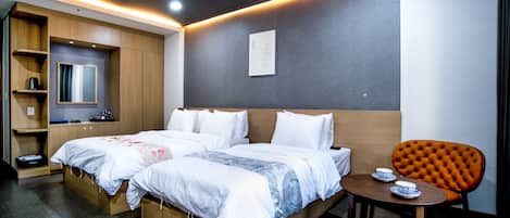 Habitación de hotel con dos camas, una mesita pequeña con una silla, un armario y un espejo.