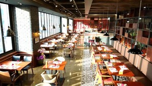 Un restaurante espacioso con múltiples mesas y sillas, ventanas amplias y un suelo con diseño.