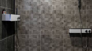 A modern shower area with a tiled wall, a handheld showerhead, and a control panel.