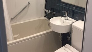 A modern bathroom with a bathtub, a sink, and a toilet. - Omura Station Hotel Nagasaki Airport (Omura)