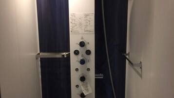 A shower stall with a handheld showerhead, a wall-mounted showerhead, and control knobs.