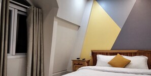 A bedroom with a bed, a nightstand, and a geometric wall design. - Hoang Mai Hotel (Da Lat)