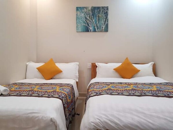 A hotel room with two single beds, each with a patterned bedspread and a white pillow. - Hoang Mai Hotel (Da Lat)