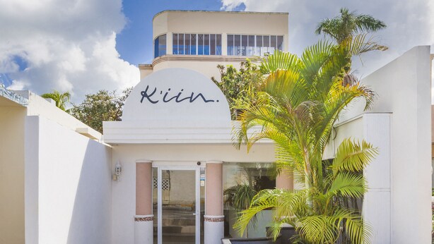 A building with a sign that reads "Klein" and a palm tree in the foreground. - Hotel Kiin Cozumel (Cozumel)