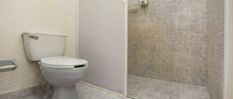Une salle de bain comprenant des toilettes, un espace douche et un sol carrelé en marbre.