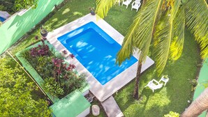 A rectangular swimming pool surrounded by lush greenery and white outdoor furniture. - Hotel Kiin Cozumel (Cozumel)