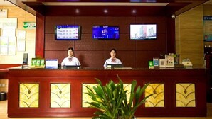 A reception desk with two staff members, a digital display board, and a potted plant. - Greentree Inn Luoyang Yichuan Yilong Avenue (Luoyang)
