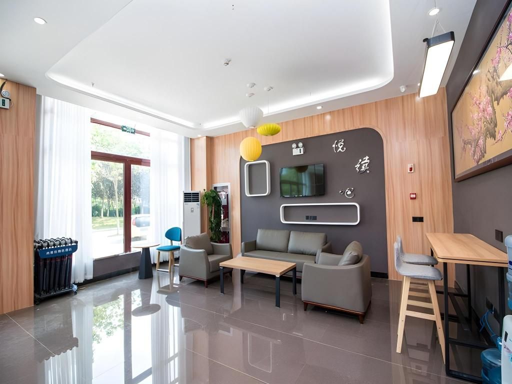 A modern hotel lobby with a reception desk, seating area, and a large window.