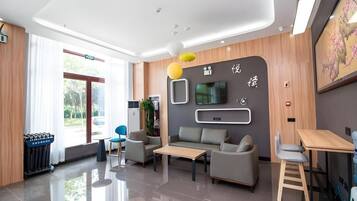 A modern hotel lobby with a reception desk, seating area, and a large window.