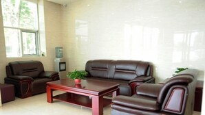 A modern living room with a brown leather sofa set, a wooden coffee table, and a small potted plant.