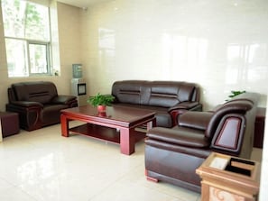 A modern living room with a brown leather sofa set, a wooden coffee table, and a small potted plant. - Greentree Inn Baoding Qingyuan District Jianshe North Road Express Hotel (Baoding)