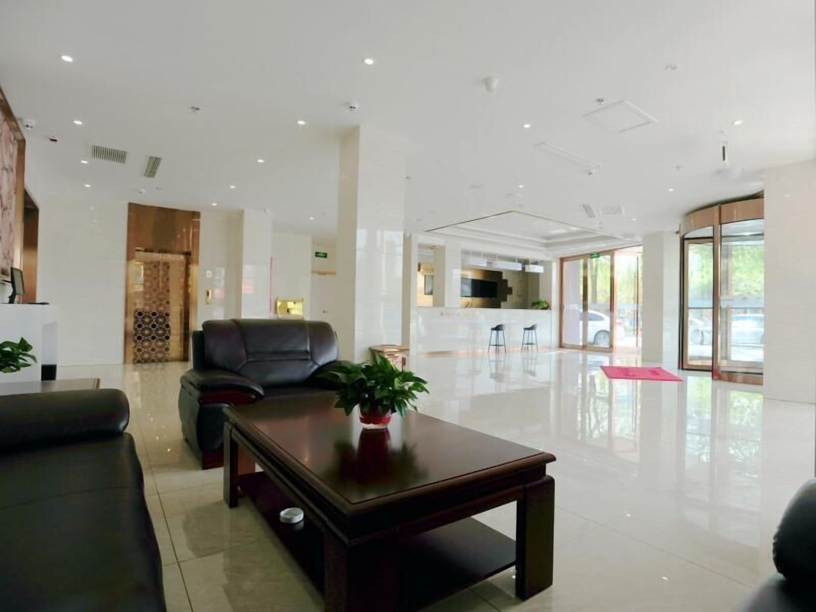 A modern hotel lobby with a leather sofa, a wooden coffee table, and a potted plant.